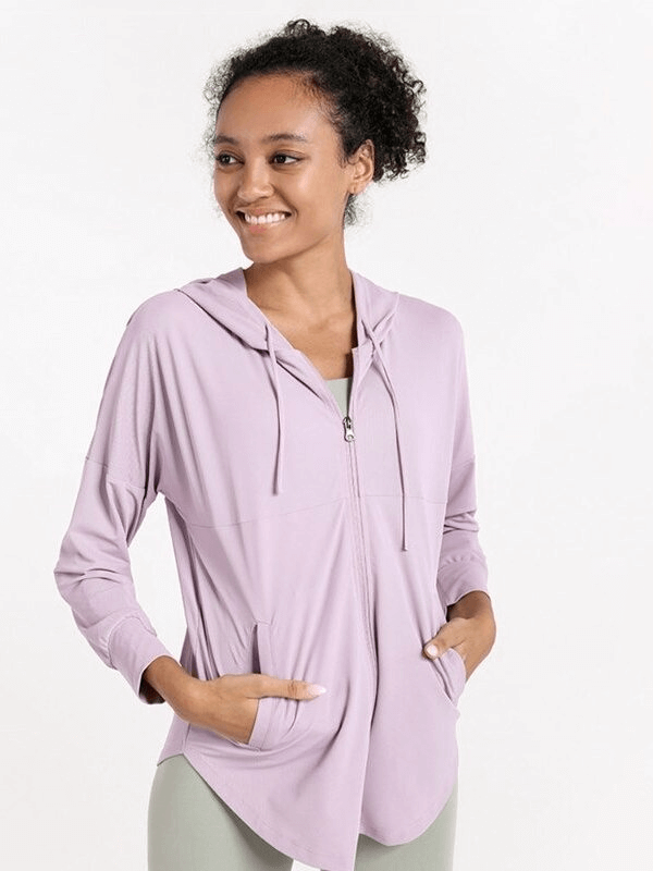 Smiling woman wearing a lilac sports loose women's jacket with hood, perfect for jogging and yoga; breathable and quick-drying design.